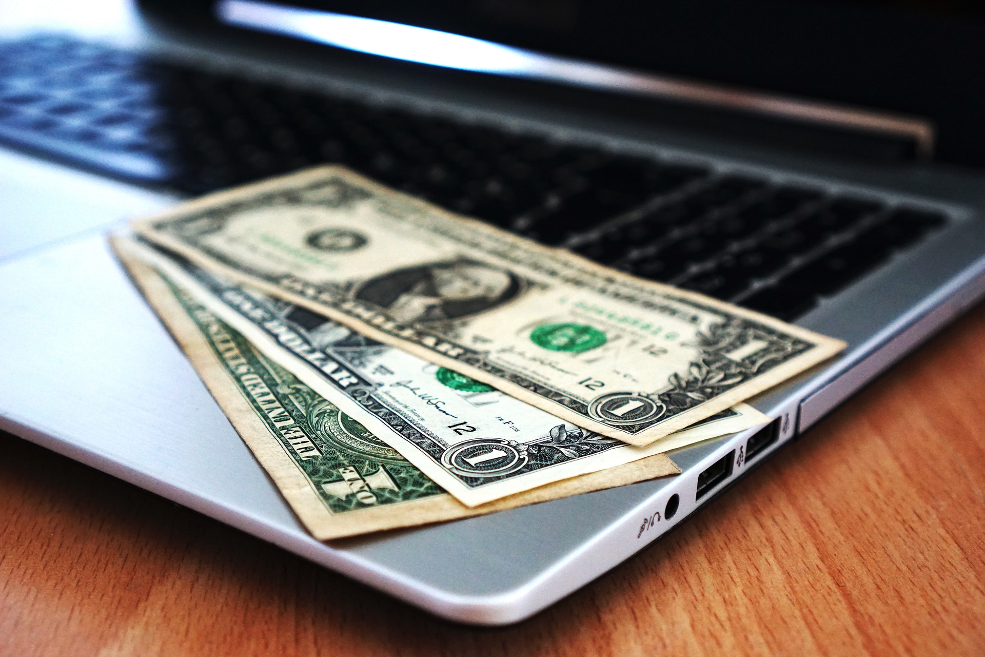 Dollar bills on top of a laptop keyboard