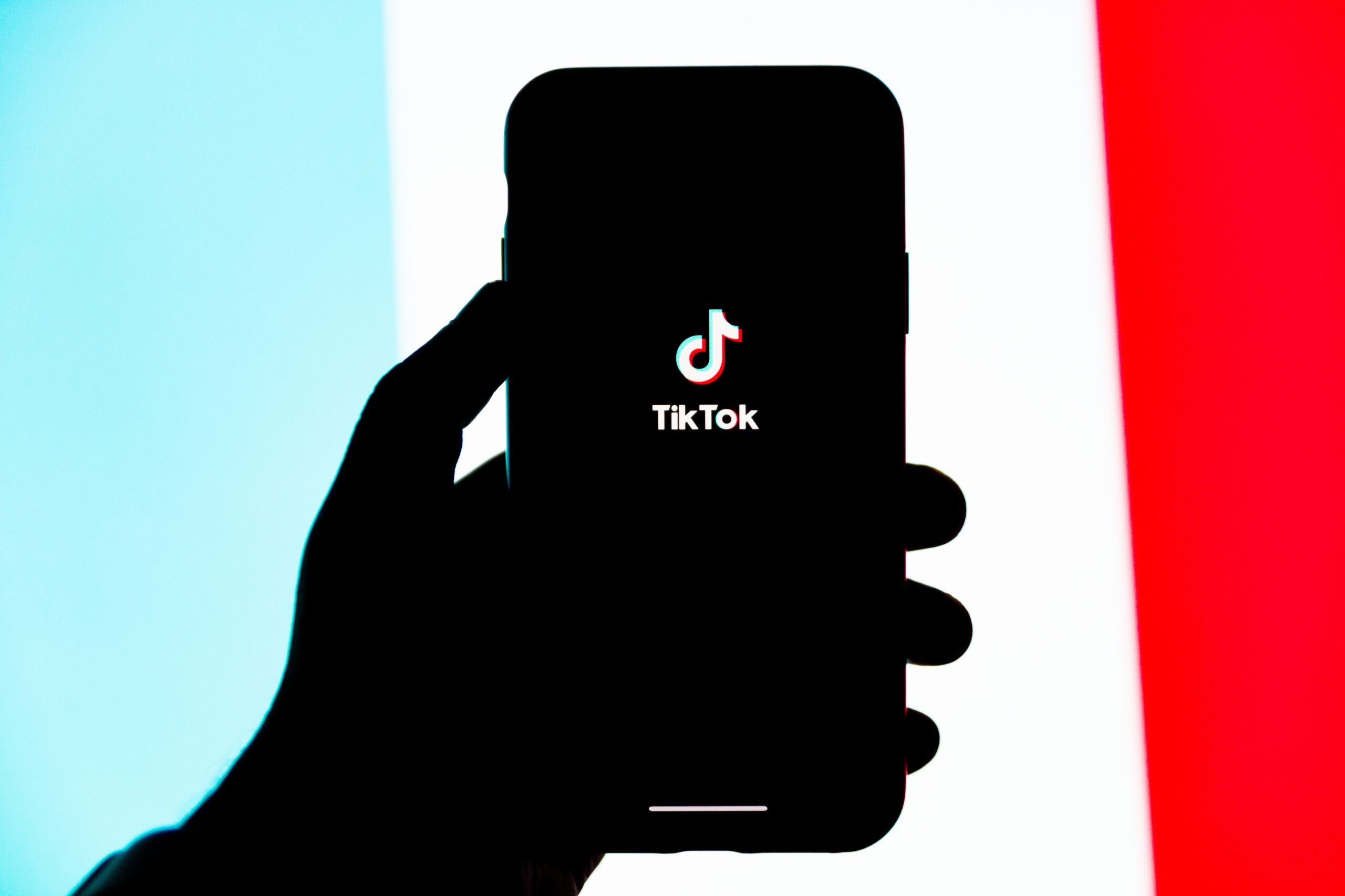How much money do musicians make on tiktok? - Intro image featuring TikTok running on iPhone with blue, white, and red background.
