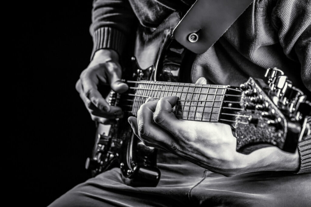 How To Tape Your Fingers For Guitar Playing - intro image- greyscale image of someone playing guitar
